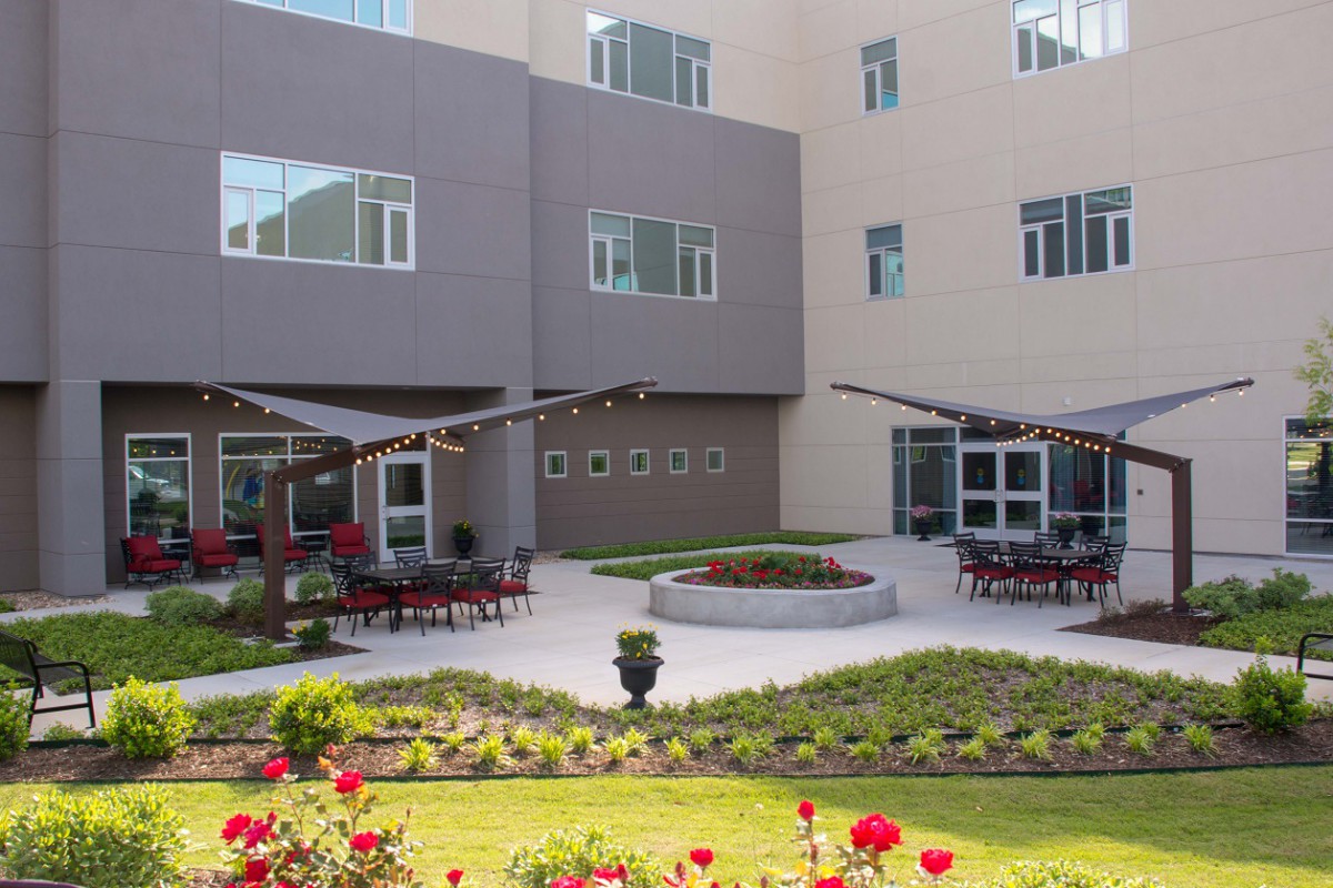 A modern building with a landscaped courtyard featuring outdoor seating and vibrant flowers.