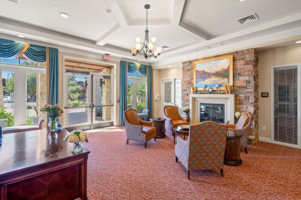 A cozy lounge area with a fireplace, elegant furniture, and large windows letting in natural light.