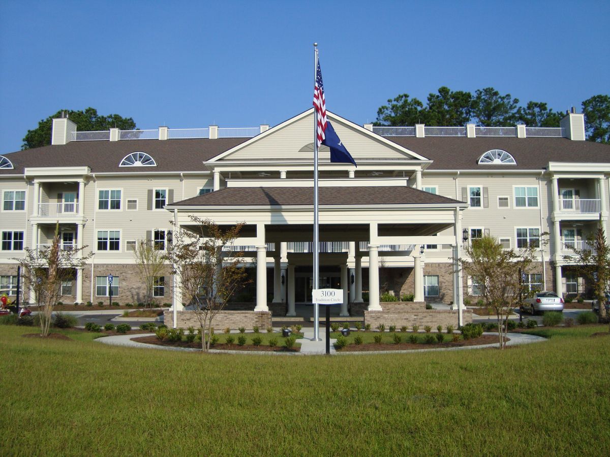 Front view of a large building with an American flag and well-maintained landscaping.