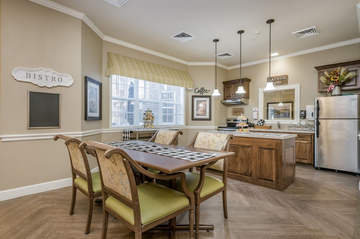 A cozy dining area connected to a kitchen with wooden furniture and pendant lighting.