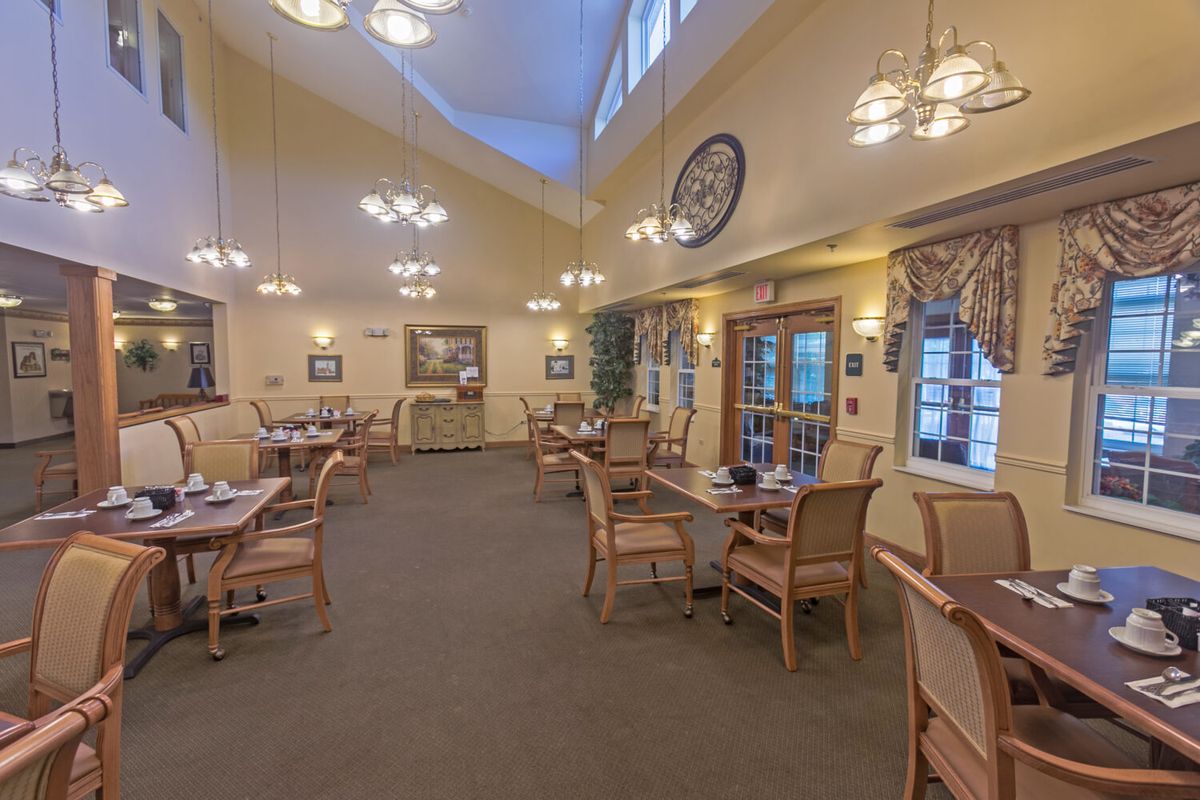 A cozy dining room with multiple tables and chairs, featuring warm lighting and elegant decor.