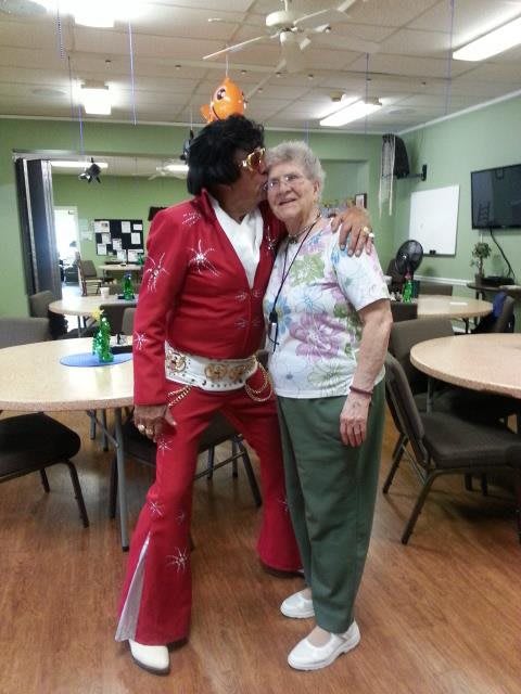 A joyful moment between a costumed performer and an elderly woman in a community setting.