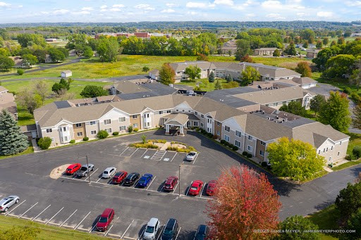 Aerial view of a residential apartment complex surrounded by lush greenery and a spacious parking lot.