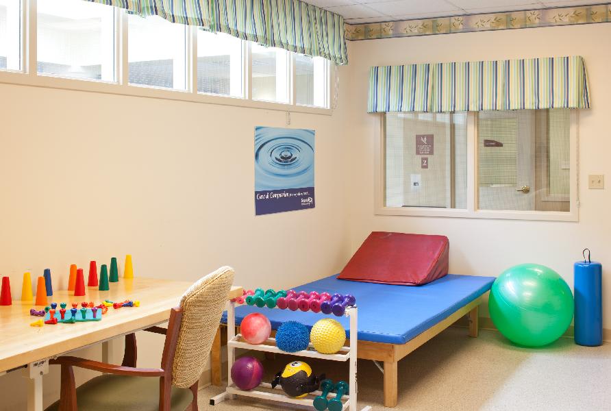 A therapy room equipped with exercise balls, an exercise table, and supportive furniture.