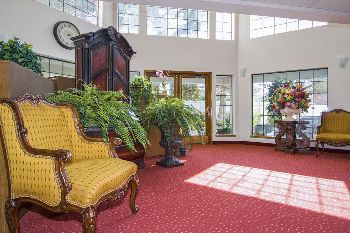 A well-lit lobby with elegant furniture, lush plants, and large windows.