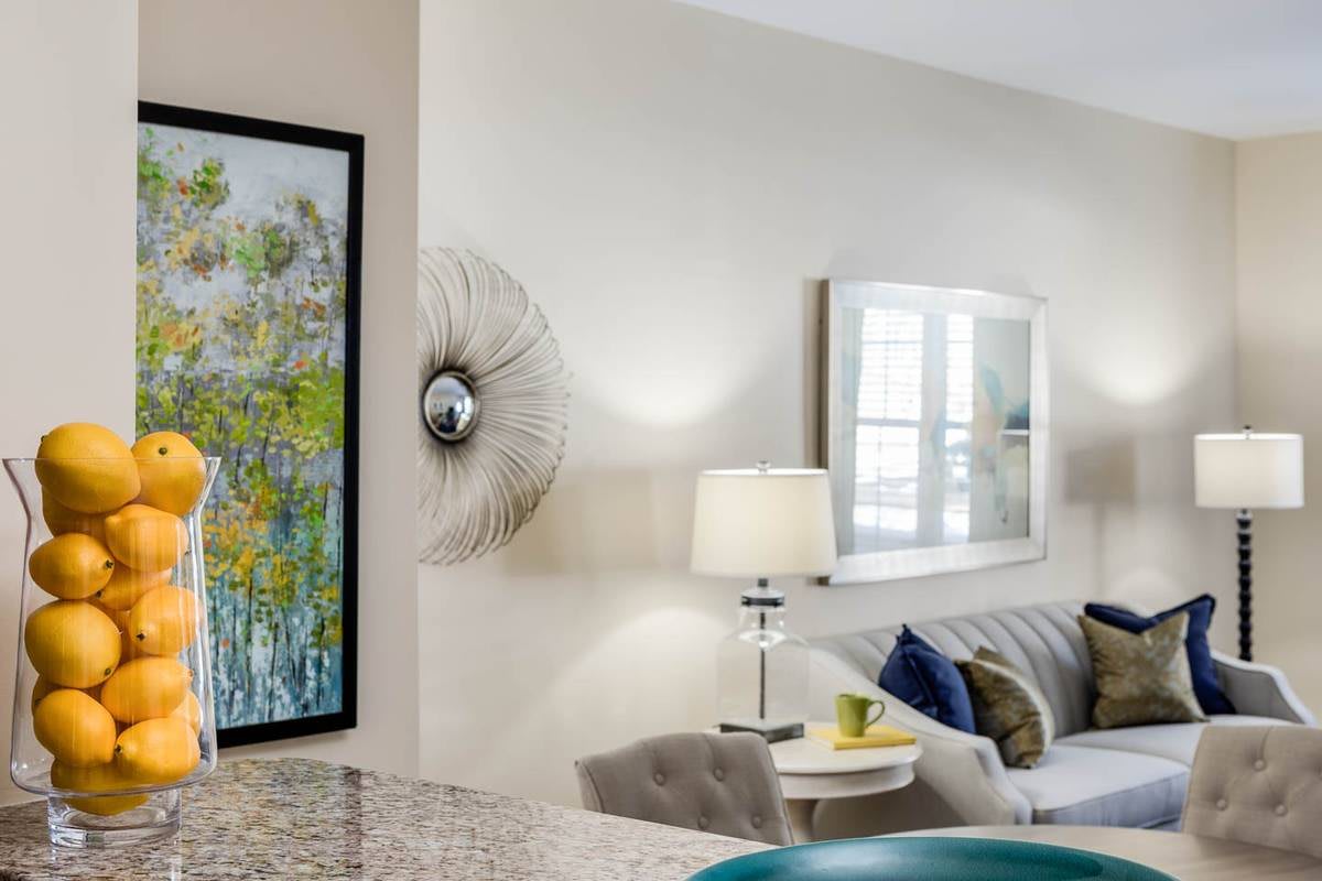 A modern living room with stylish decor, featuring a comfortable sofa, artwork on the wall, and elegant lighting.