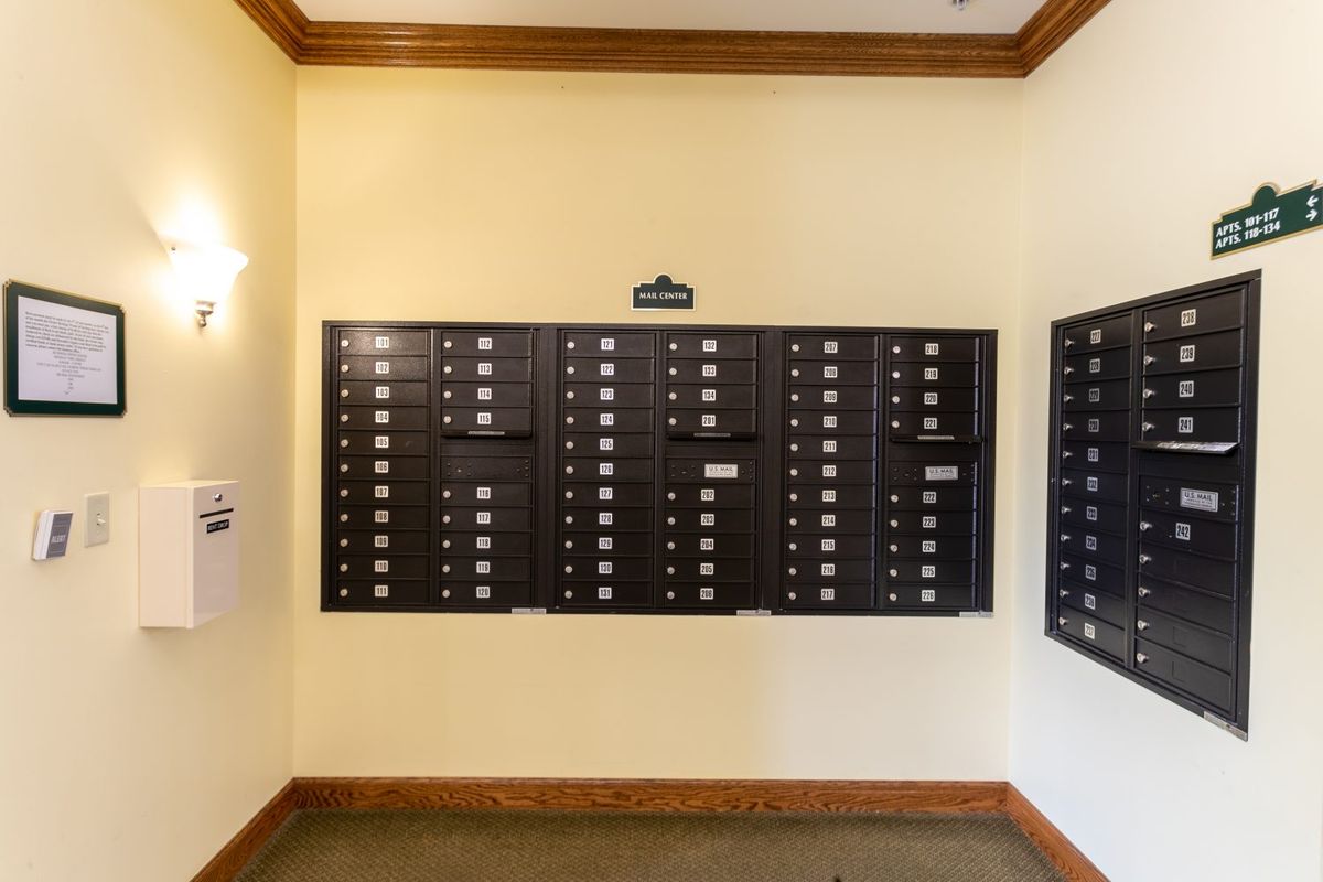 A hallway with multiple black mailboxes mounted on the wall.