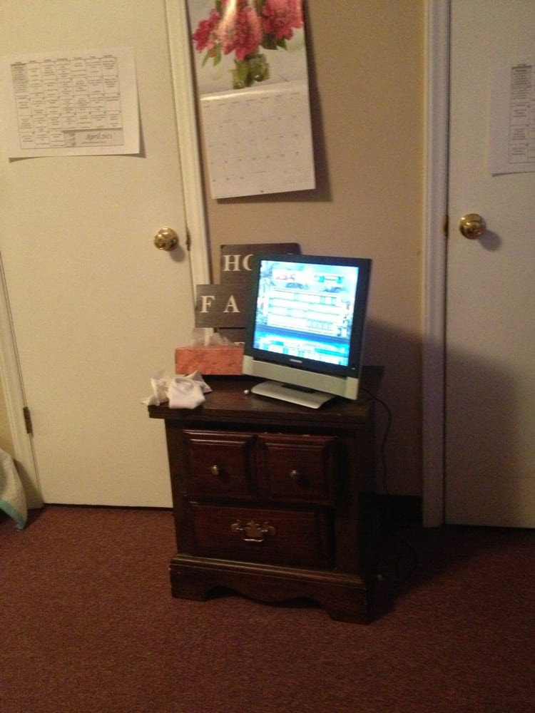 A monitor on a nightstand in a room with closed doors.