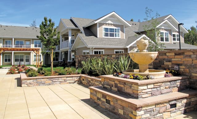 A suburban house with modern landscaping and a prominent fountain in the front yard.