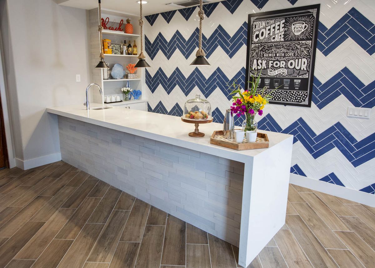 A modern kitchen space featuring a sleek white counter, vibrant flowers, and a zigzag patterned accent wall.
