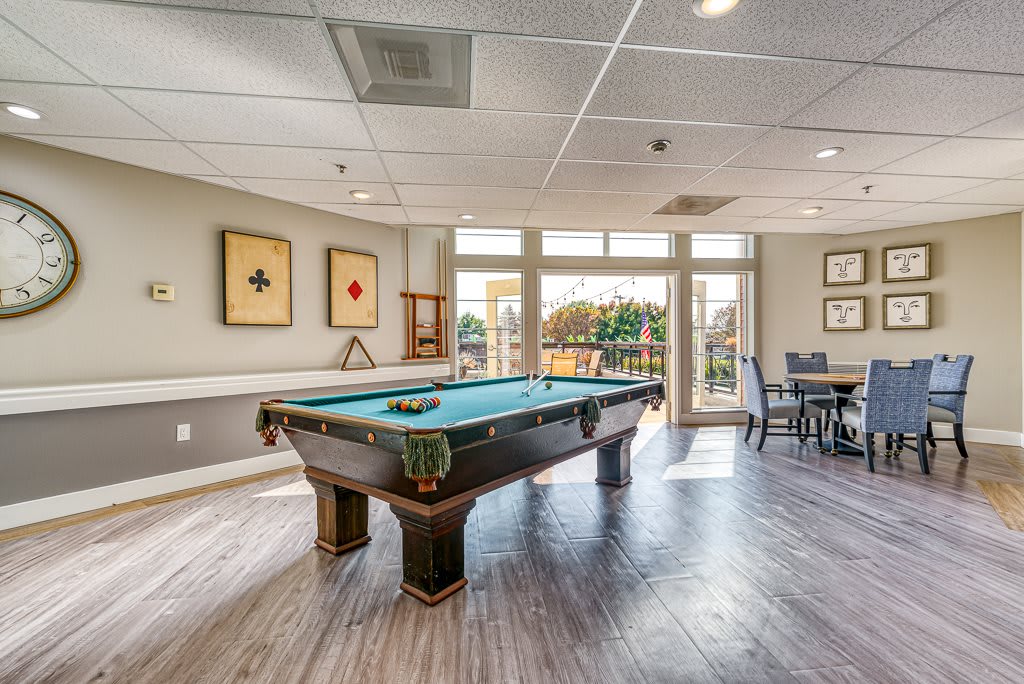 A modern recreation room featuring a pool table and stylish decor with ample natural light.