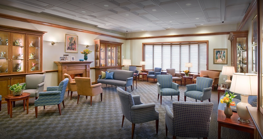 A cozy and well-furnished waiting room with multiple seating options, including chairs and sofas, set on a carpeted floor.