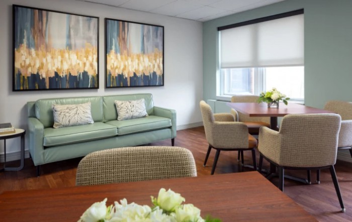 A modern living room with a cozy sofa, artistic wall decor, and a dining area featuring a round table and chairs.
