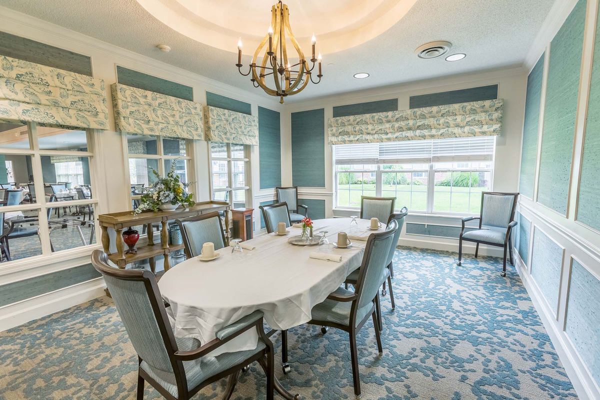 A beautifully decorated dining room featuring a chandelier, elegant furniture, and large windows that provide ample natural light.