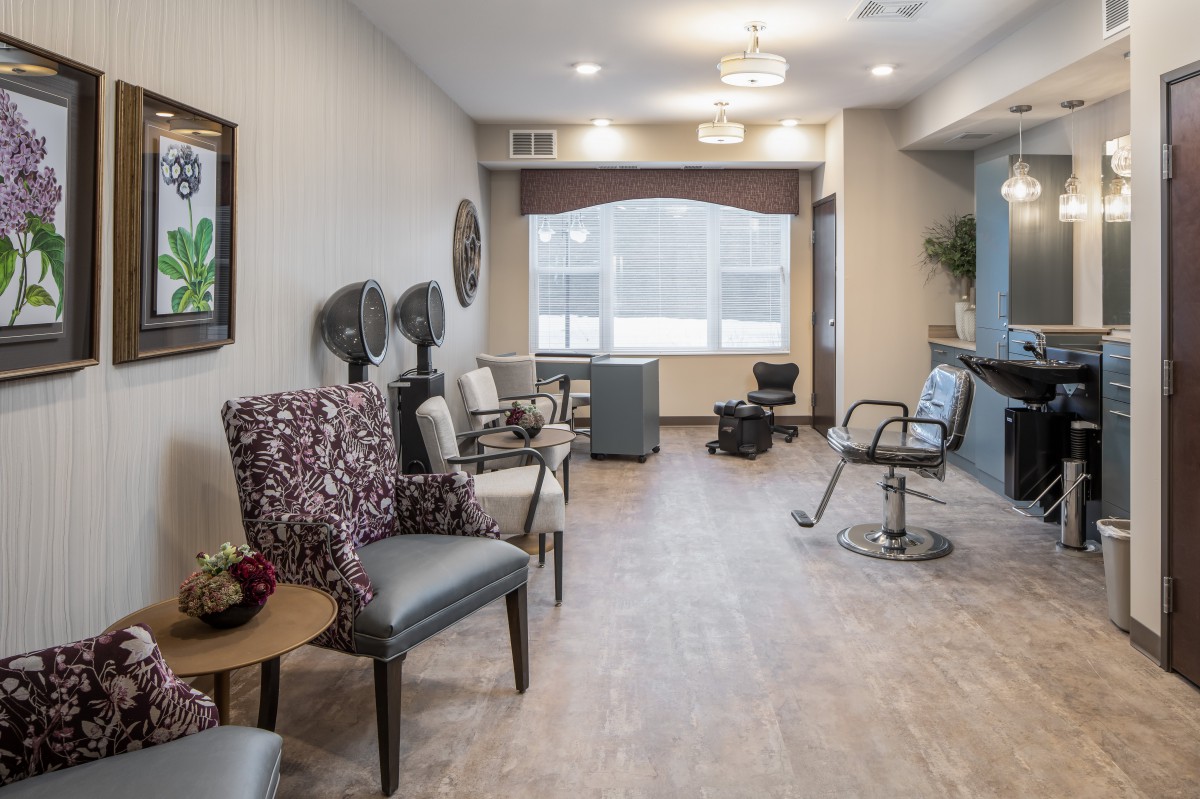 A modern and well-lit hair salon interior with styling chairs, mirrors, and hair dryers.