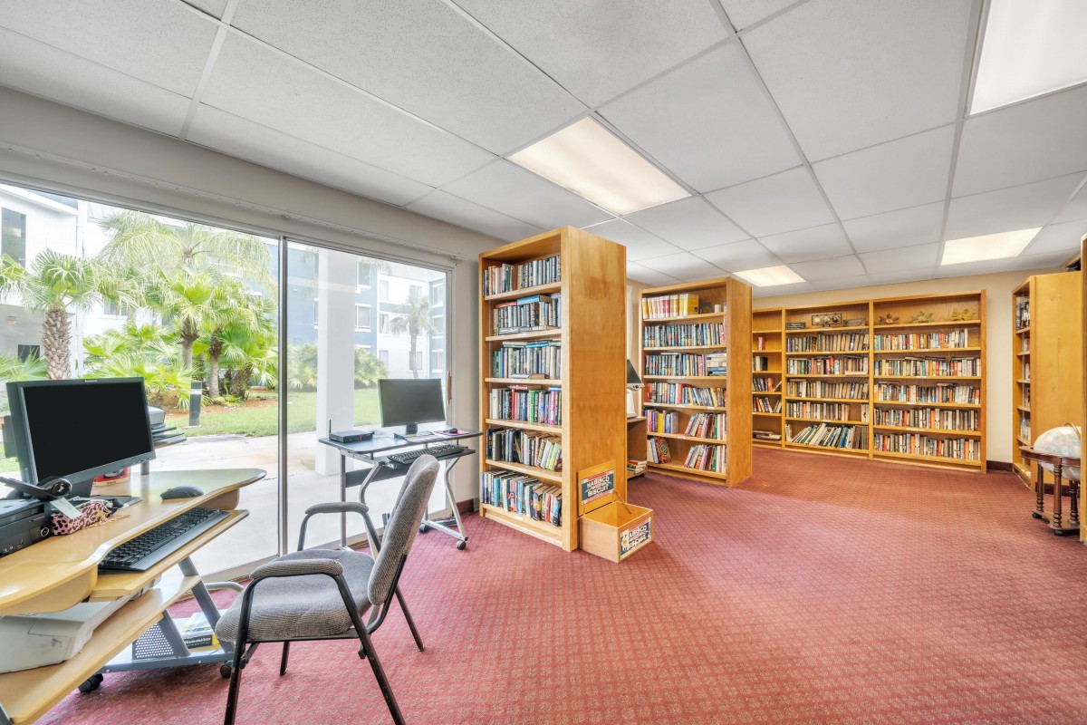 A quiet library room with bookshelves and a computer station by the window.