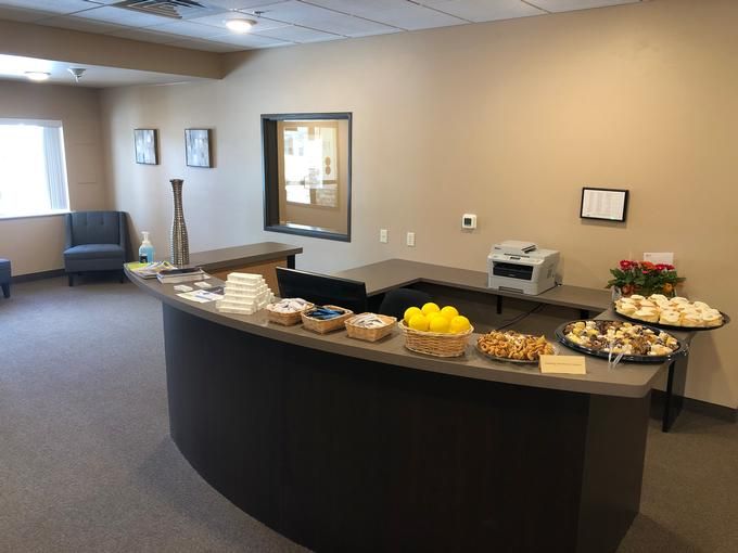 A reception area with a curved desk, seating, and refreshments.