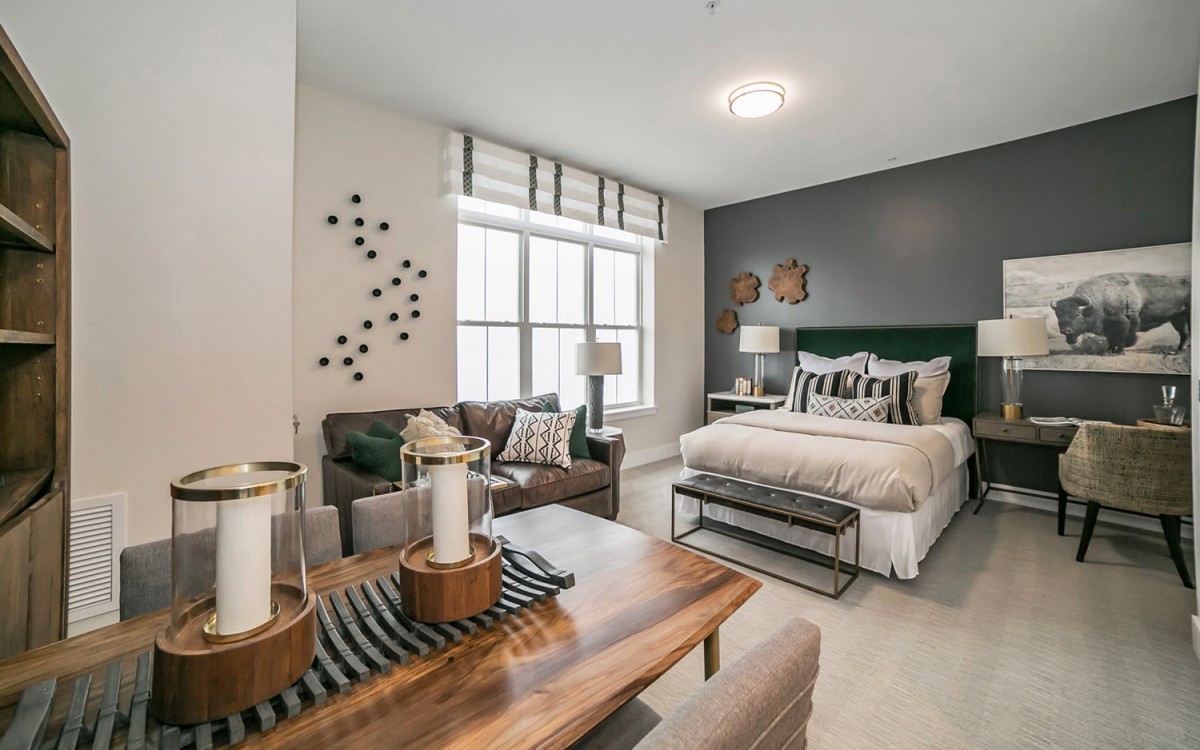 A modern and cozy bedroom with elegant interior design, featuring a comfortable bed, plush seating, and decorative elements.
