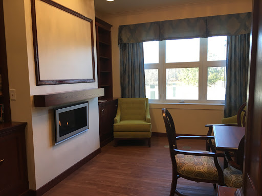A cozy interior space featuring a green chair, wooden flooring, and a warm window view.