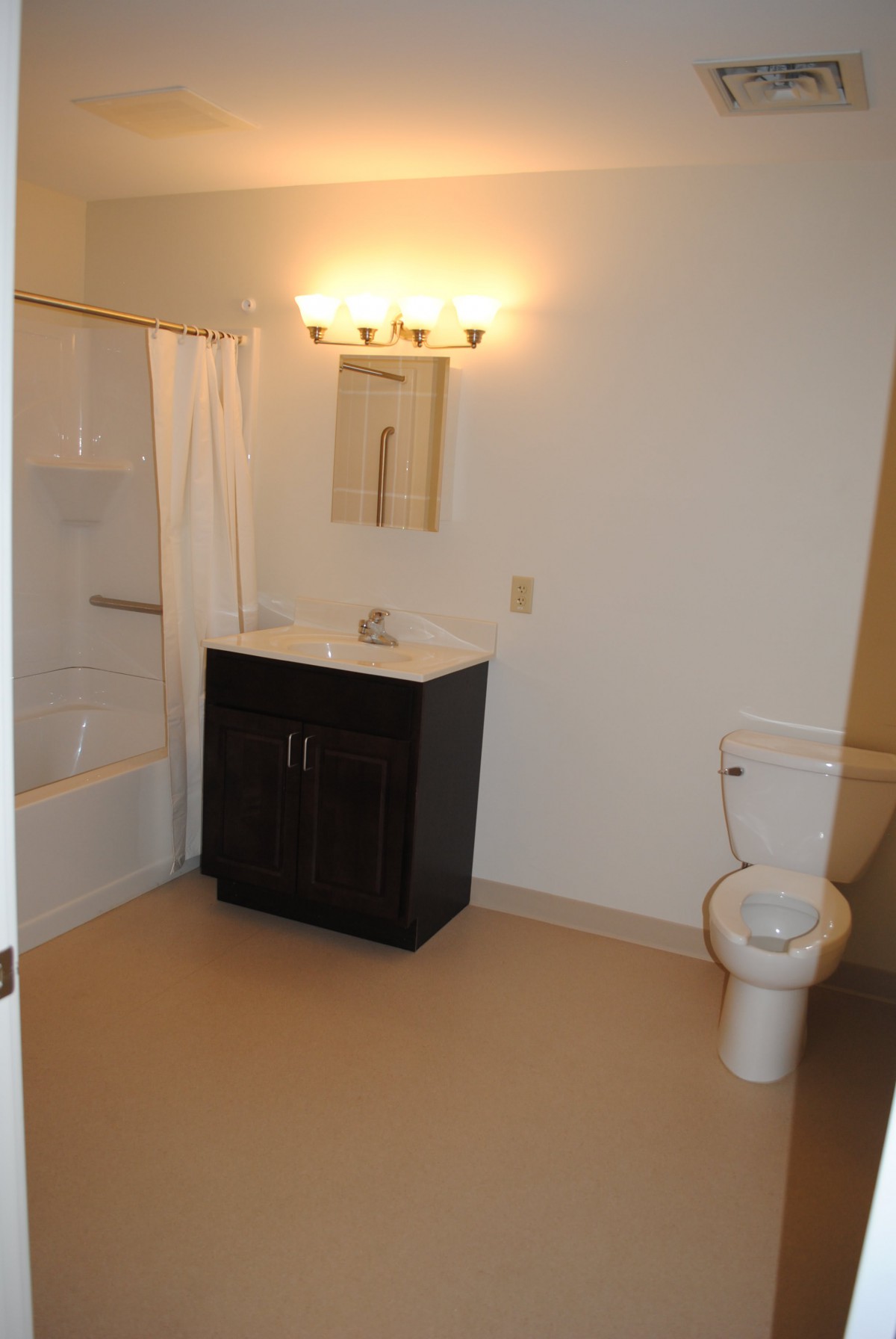 A clean and simple bathroom with a sink, toilet, and bathtub.