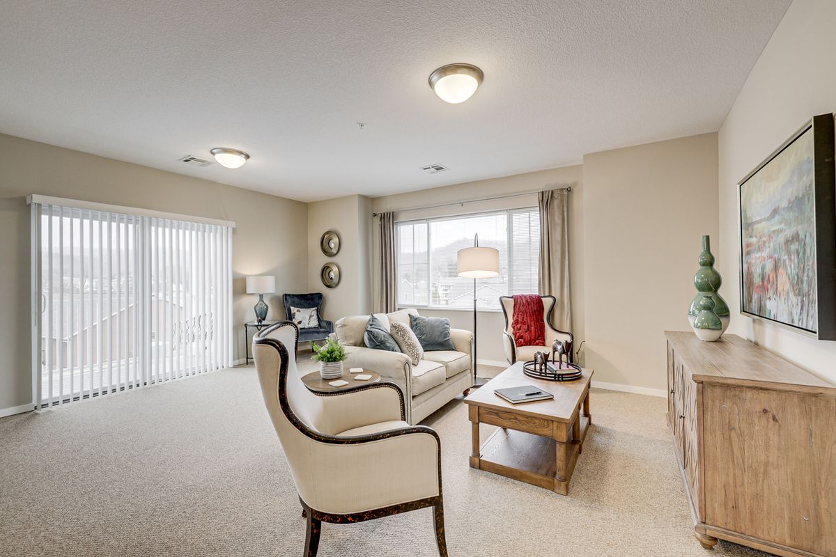 A cozy living room featuring a sofa, armchairs, and a coffee table in front of a large window.