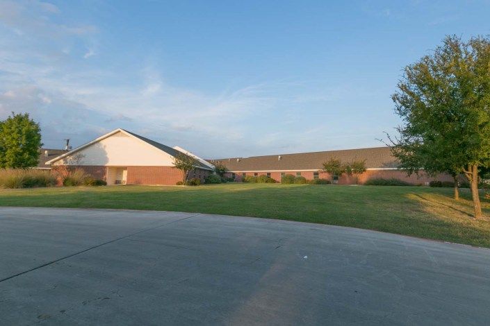 A suburban building with a large lawn under a clear sky.