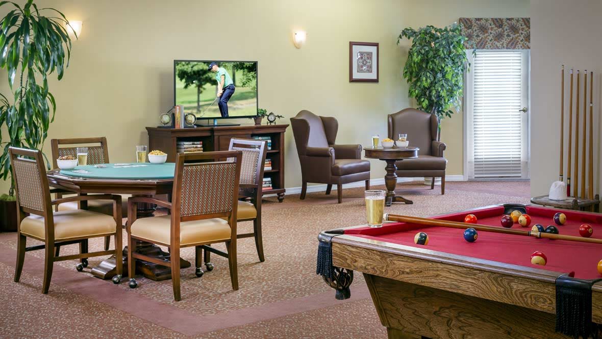 A cozy common area featuring a pool table, comfortable seating, and a television.