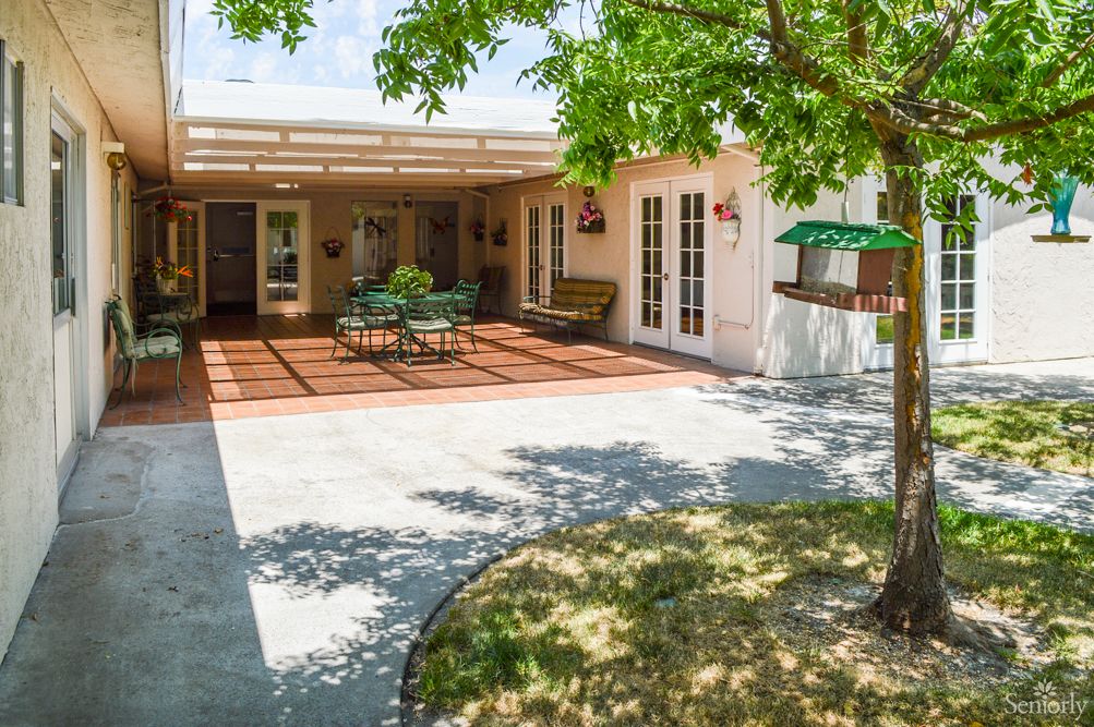 A sunny backyard patio area with outdoor furniture and a shaded deck.