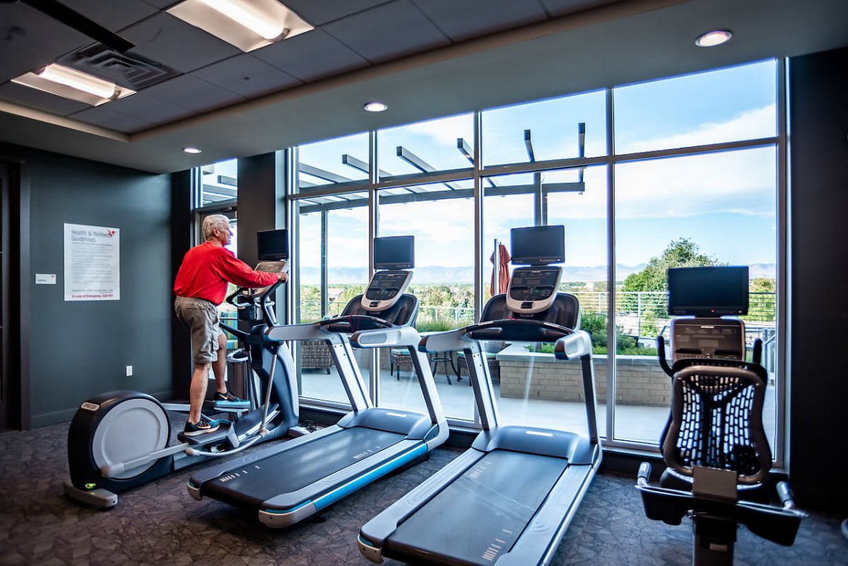 A fitness center with treadmills and exercise equipment, featuring large windows with a scenic view.