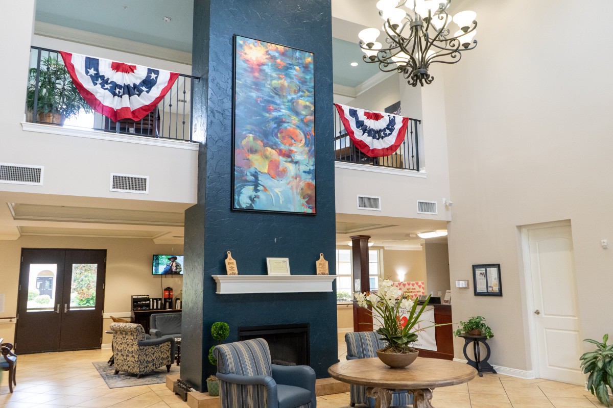 A spacious and elegantly decorated lobby featuring a chandelier, artwork, and comfortable seating.
