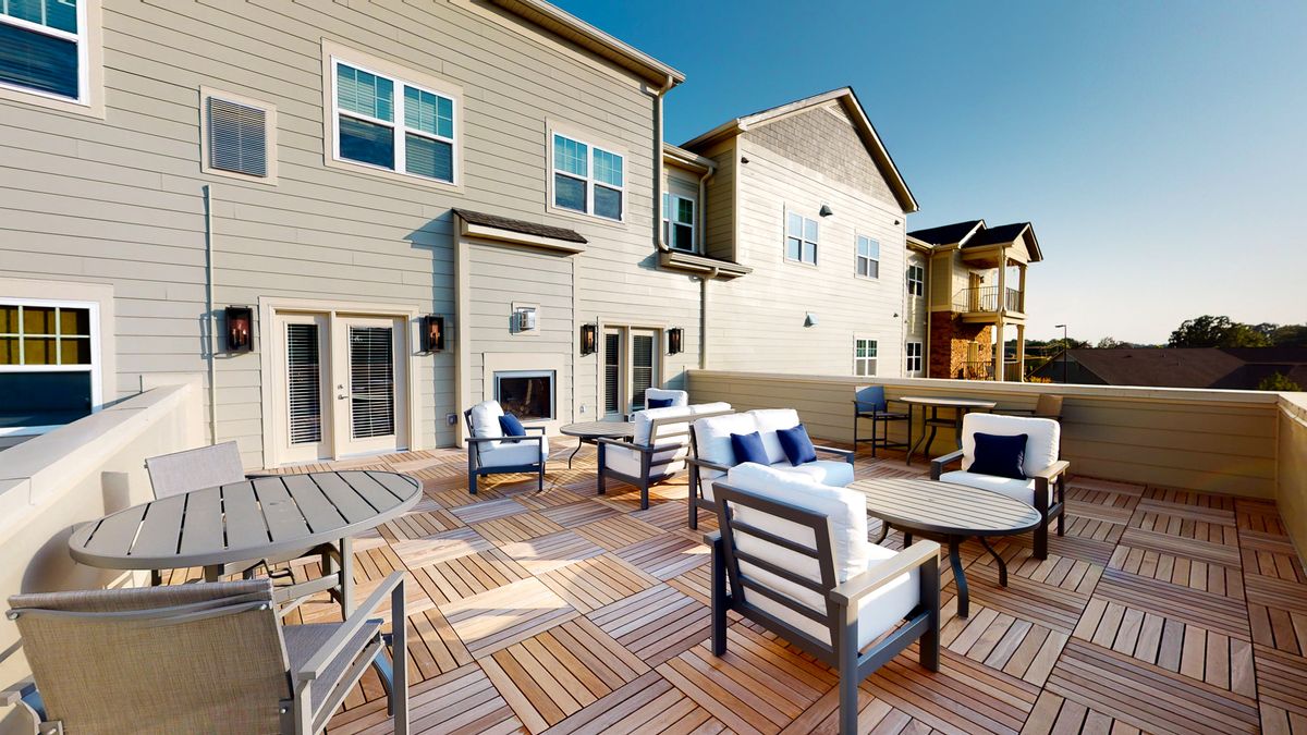 A spacious outdoor deck area with comfortable seating and tables, attached to a residential building.