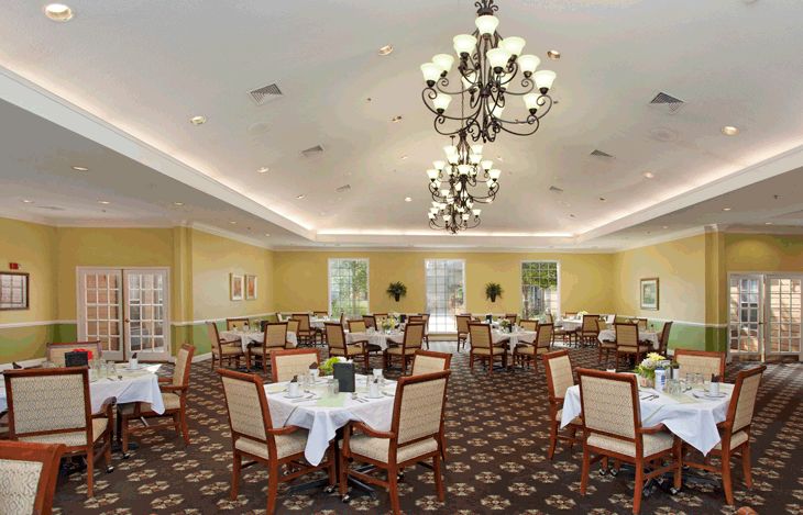 A spacious and elegantly decorated dining room with chandeliers, set with tables and chairs.