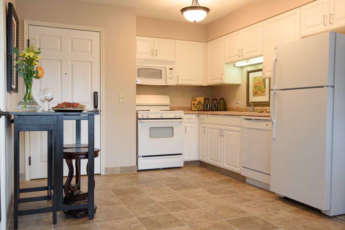 A modern kitchen with white cabinets, appliances, and a small kitchen island.