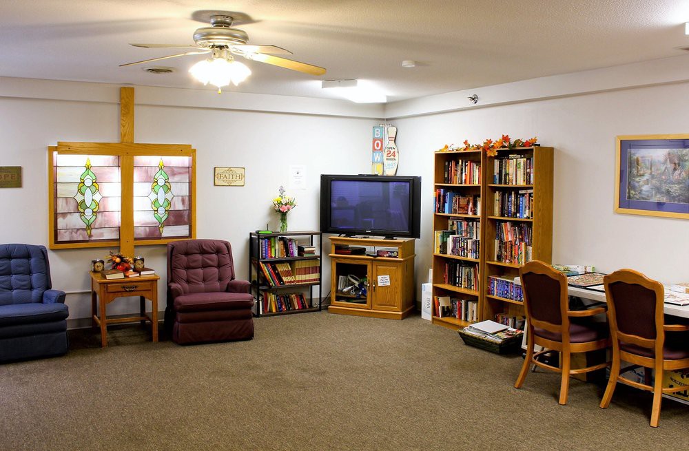 A cozy living room with a television, bookshelves, and comfortable seating.