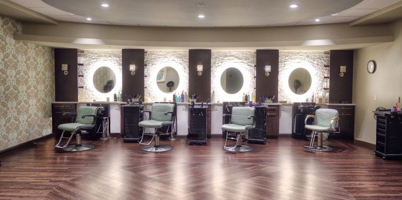 A modern barbershop with stylish chairs and illuminated mirrors.