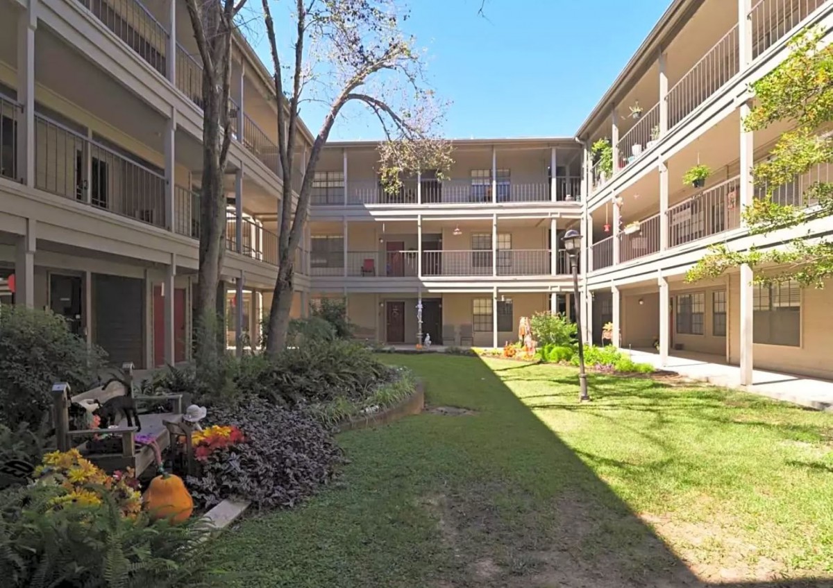 A sunny apartment courtyard with plants and open walkways.