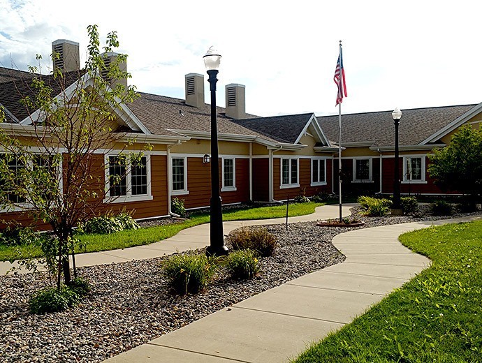 A picturesque building with a winding pathway, well-maintained garden, and flagpole.