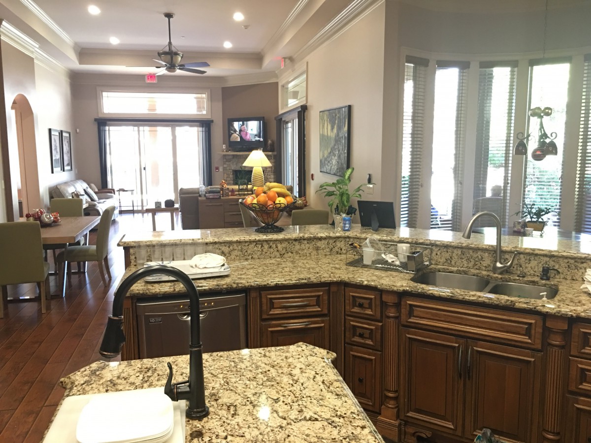 A modern open-concept kitchen with granite countertops overlooking a cozy living area.