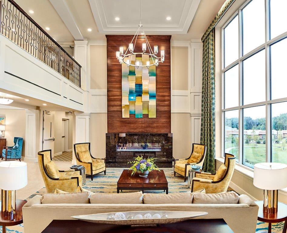 A luxurious living room with elegant furniture, high ceilings, and a large modern art piece above the fireplace.