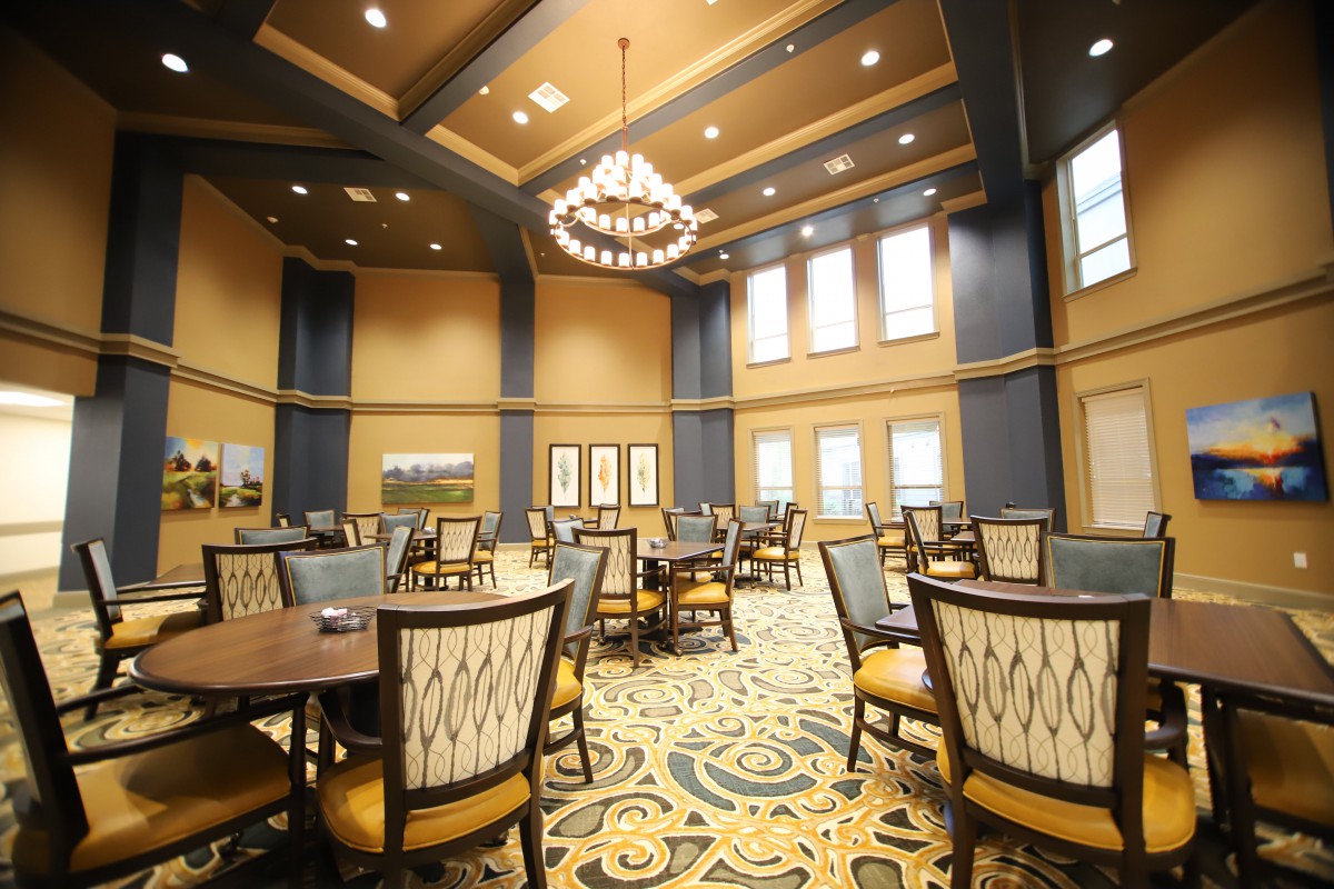 A spacious and elegantly decorated dining room with multiple tables and a large chandelier.