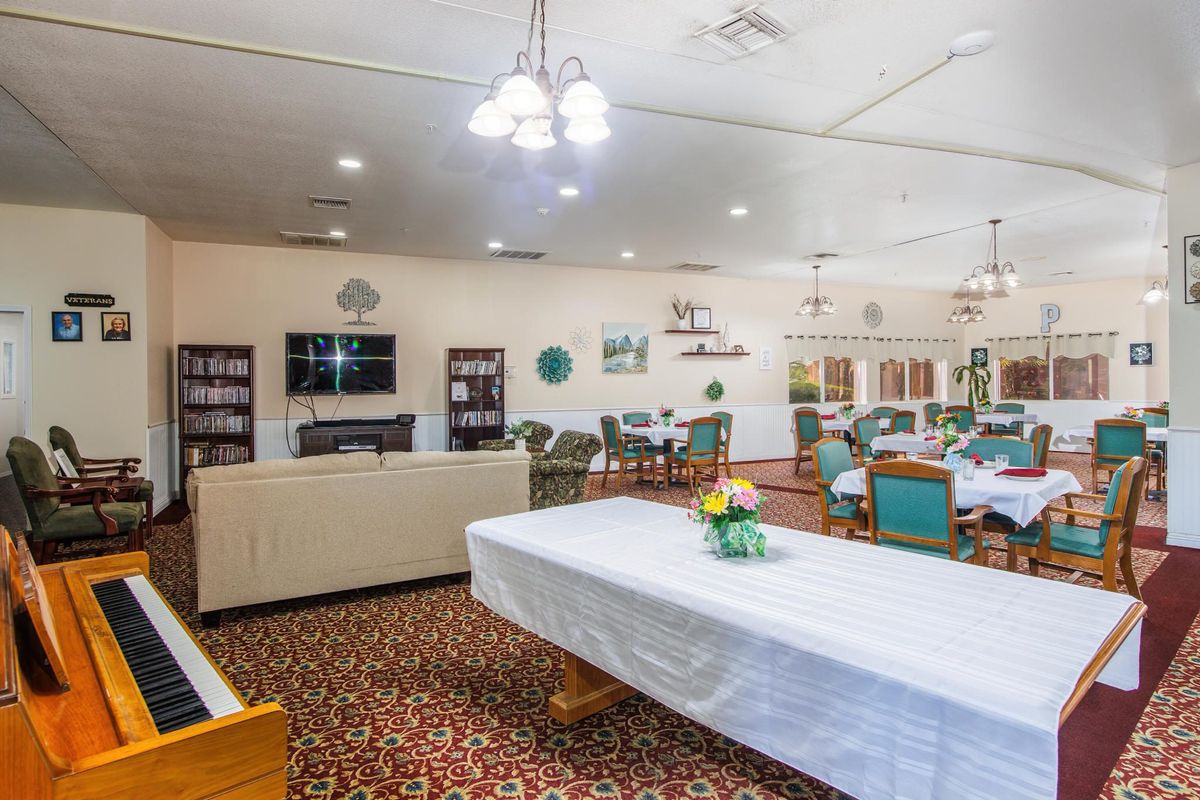 A spacious communal dining and living area with tables, chairs, and a television.