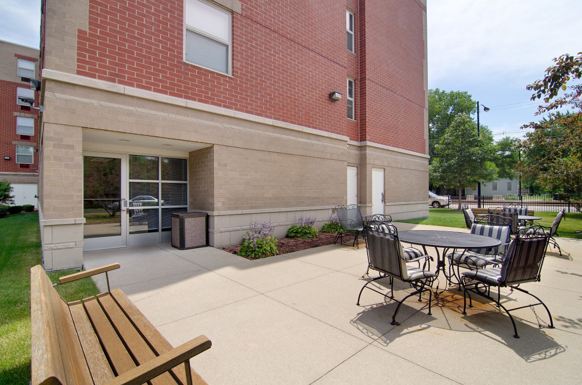 Outdoor patio area with seating and tables next to a brick building.