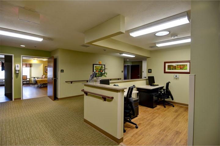 A modern reception area with desks and chairs, featuring a well-lit corridor.