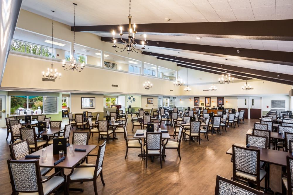 A spacious dining hall with elegant chandeliers and neatly arranged tables and chairs.