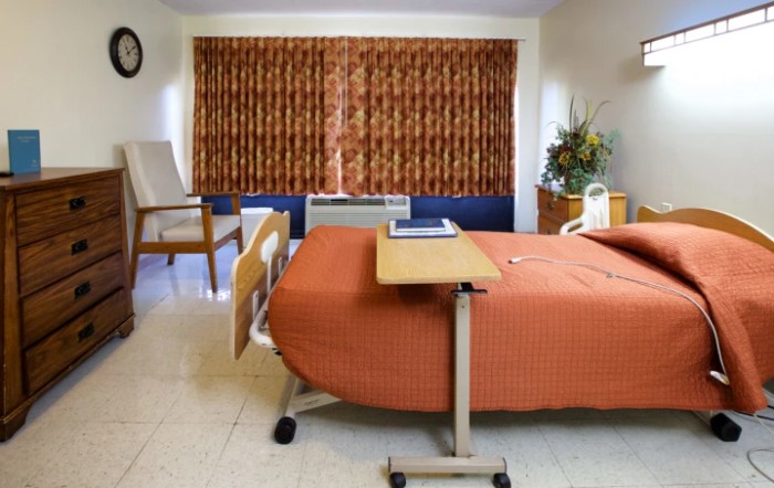 A hospital room with a bed, side table, and curtain-covered window.