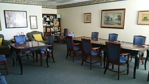 A well-furnished meeting room featuring tables and chairs, with a bookshelf in the background.