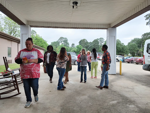 A group of people gathering outside a shopping center, engaged in conversation and social activities.