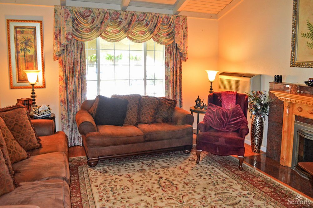 A cozy living room with a sofa, armchair, and a large window adorned with curtains.