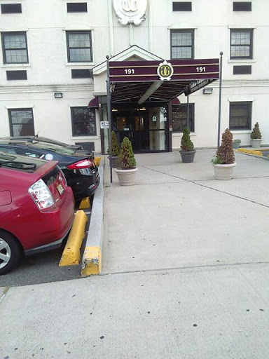 A view of a hotel entrance with parked cars in front.
