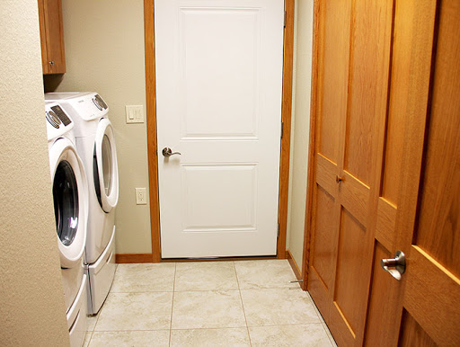 A cozy laundry room featuring a washing machine and dryer, with wooden doors and tiled flooring.